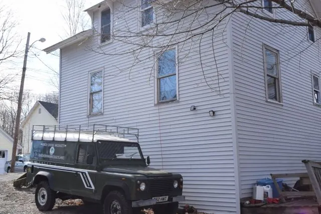 White clapboard house with an old Land Rover beside it